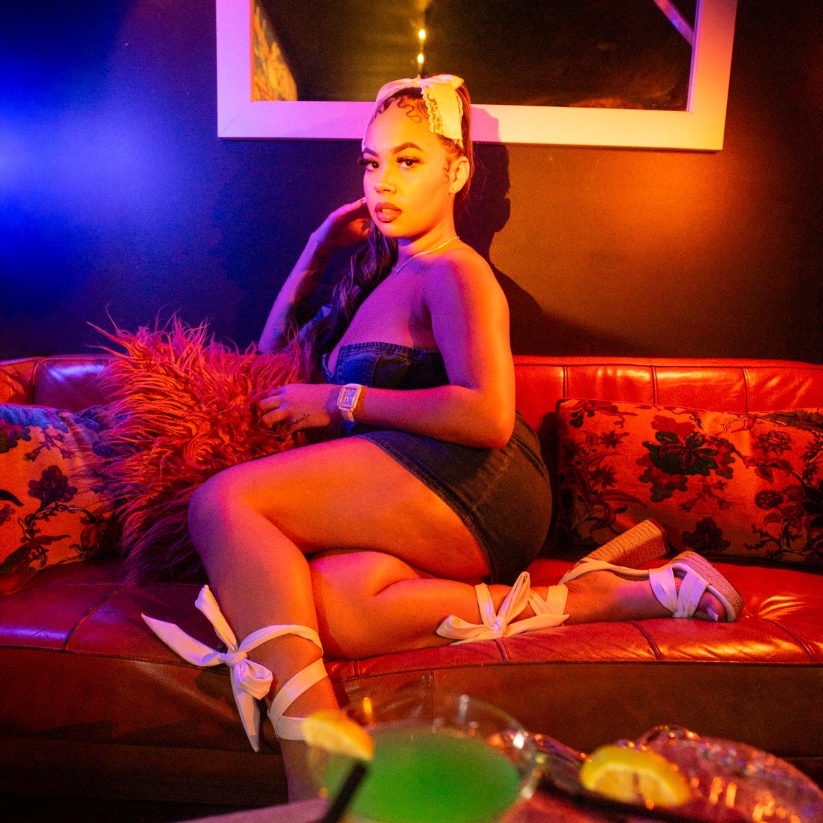A woman sits on a red couch under blue and orange light during the canna&cid listening event at Tiny House