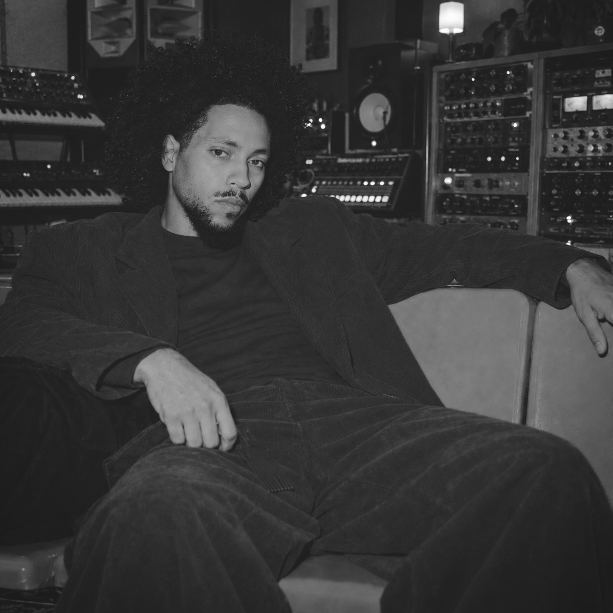 Black-and-white portrait of Chikadibia Ebirim seated in a recording studio surrounded by audio equipment