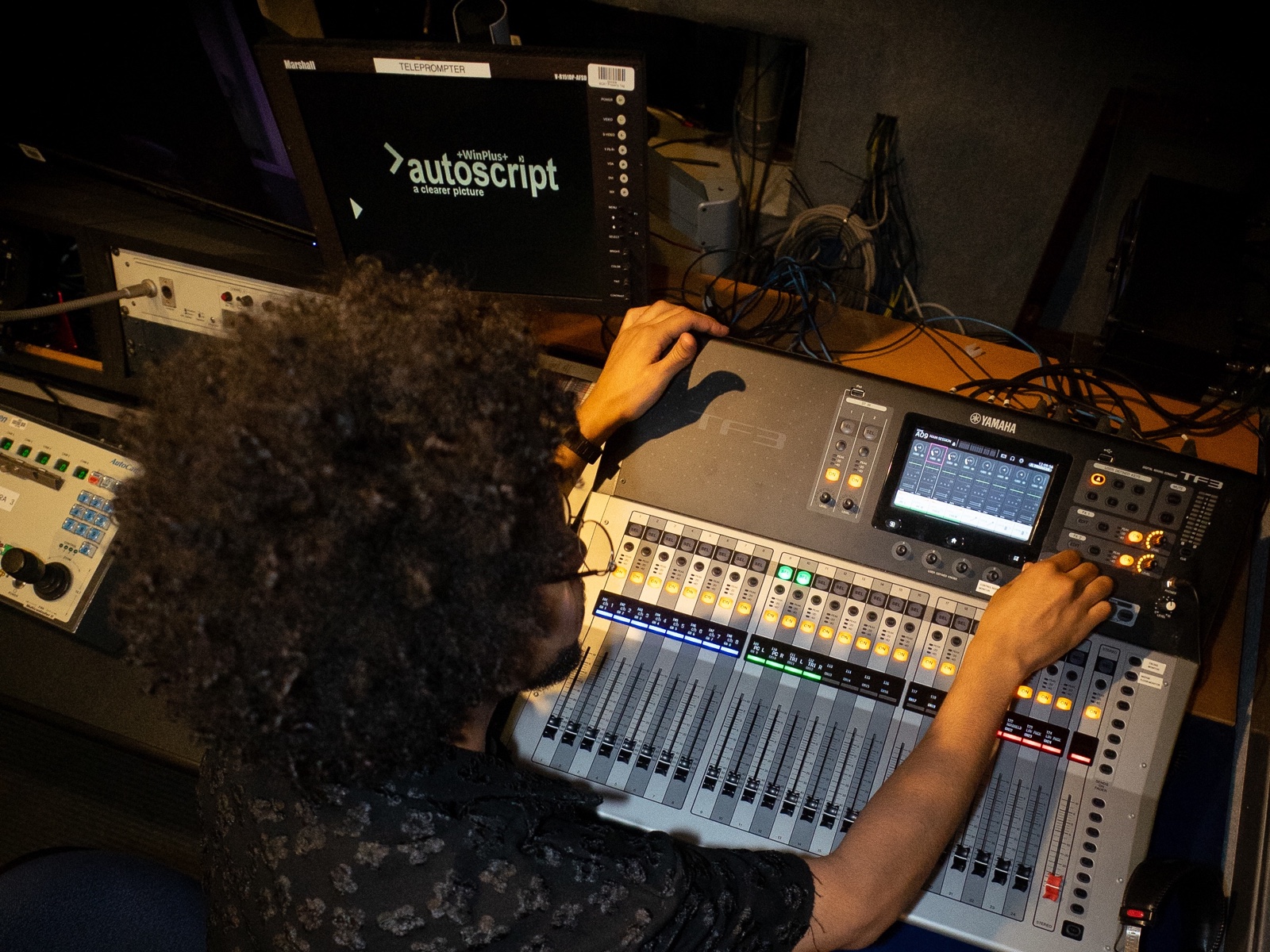 Overhead view of Chi operating a Yamaha TF3 mixing console in a production control booth